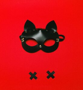 Máscara BDSM estilo gato negro con fondo rojo y cintas negras en forma de X